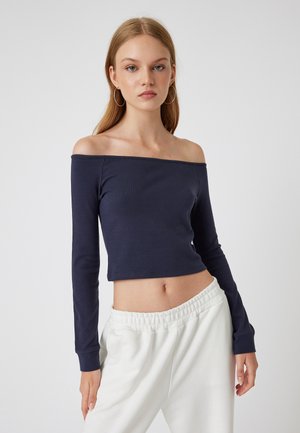 Marine off-the-shoulder crop top met lange mouwen, gemaakt van zachte stof. Gepaard met witte, elastische taillebroek.