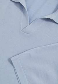 Ljust blått, texturerat stickat polo skjorta med V-ringning och korta ärmar med välbehandlede muddar och sömnadsdetaljer.