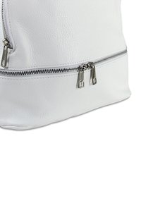 Weißer Lederbeutel mit strukturierten Oberflächen, ausgestattet mit zwei silbernen Reißverschlüssen an der Vorderseite und einem glatten, abgerundeten Boden.