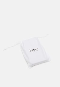 Pochette blanche à cordon en tissu doux, avec un logo imprimé qui indique « FURLA » et « SINCE 1927 ITALY ». Design simple et minimaliste.