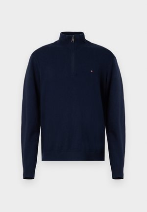 Navyblauwe gebreide trui met een hoge kraag en kwart rits. Beschikt over een klein logo op de borst en geribbelde manchetten en zoom.