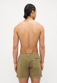 Calças de banho caqui com um cós elástico e bolso nas costas, tecido leve, comprimento até a metade da coxa e um design simples.