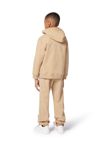 Beige sweatshirt met capuchon en geborduurd 'LANVIN' logo, gecombineerd met bijpassende sweatpants met zijdetails, afgemaakt met witte sneakers.