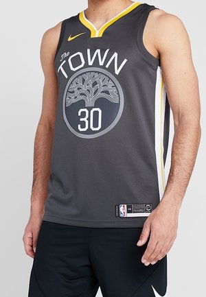 Tmavě šedý basketbalový dres bez rukávů s nápisem „The Town“, logem stromu, číslem 30, žlutým lemováním a odznaky Nike a NBA, nošený osobou.