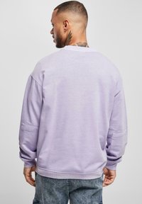 Felpa viola chiaro con vestibilità comoda, maniche lunghe, polsini a costine, collo arrotondato e una piccola tasca laterale.