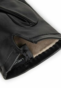 Gant en cuir noir avec un poignet ouvert, doublé de tissu beige. Présente une texture lisse et une couture le long des bords. Étiquette de marque visible.