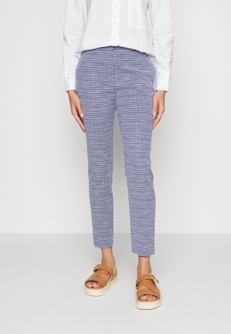 Lehké, vzorované kalhoty v modro-bílé barvě se slim fit. Kombinované s plochými sandály v tan barvě, které mají detail přezky.