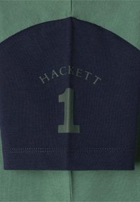 T-shirt med kort ärm som har en grön och marinblå färgblockdesign, med "HACKETT" och siffran "1" tryckt i en kontrasterande färg.