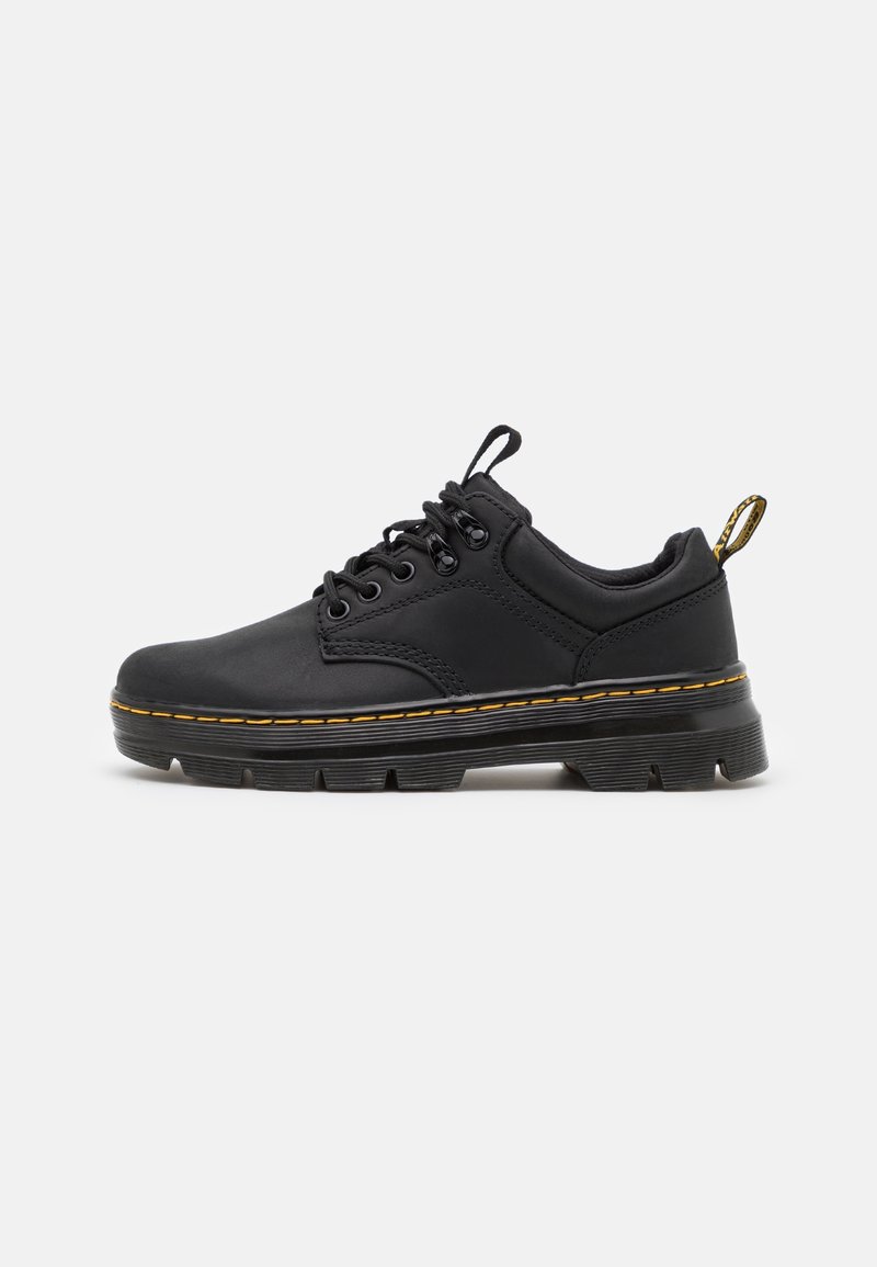Chaussure basse noire à lacets avec semelle épaisse, coutures jaunes et languettes sur la languette et le talon, montrée de profil sur fond blanc.