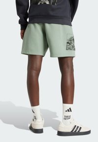 Mint green shorts with a side pocket featuring a black-and-white graphic, paired with white socks and cream shoes with black stripes.