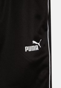 Schwarze Sportshorts aus glattem Stoff, mit einem weißen Puma-Logo und zwei weißen Seitenstreifen für den Kontrast.