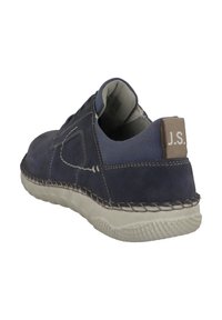 Mörkblå mockaskor med en texturerad grå tygkrage, kontrasterande vit sömnad och en beige hälaccent. Har en gummisula med greppstruktur.