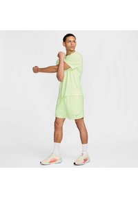Vaateyhdistelmä, joka koostuu vaaleanvihreästä urheiluhaalari yhdistelmästä, johon kuuluu lyhyet hihaiset paidat ja shortsit. Sisältää Nike-logon, hengittävän kankaan ja elävät värikoristeet kengissä.