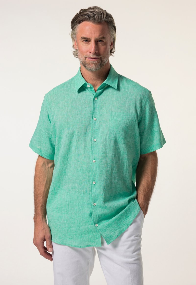 Košile s krátkým rukávem a knoflíky ve světle zeleném lnu s texturovaným povrchem a náprsní kapsou, spárovaná s bílými kalhotami.