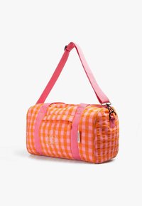 Sac de sport à damier orange et rose avec une bandoulière et des poignées roses, présentant un petit motif de tête de mort et os croisés sur le côté.
