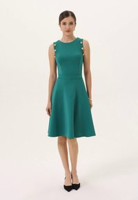 Türkisfarbenes ärmelloses Kleid mit einem taillierten Oberteil und ausgestelltem Rock, versehen mit goldenen Knöpfen auf den Schultern und einer glatten, dehnbaren Textur.