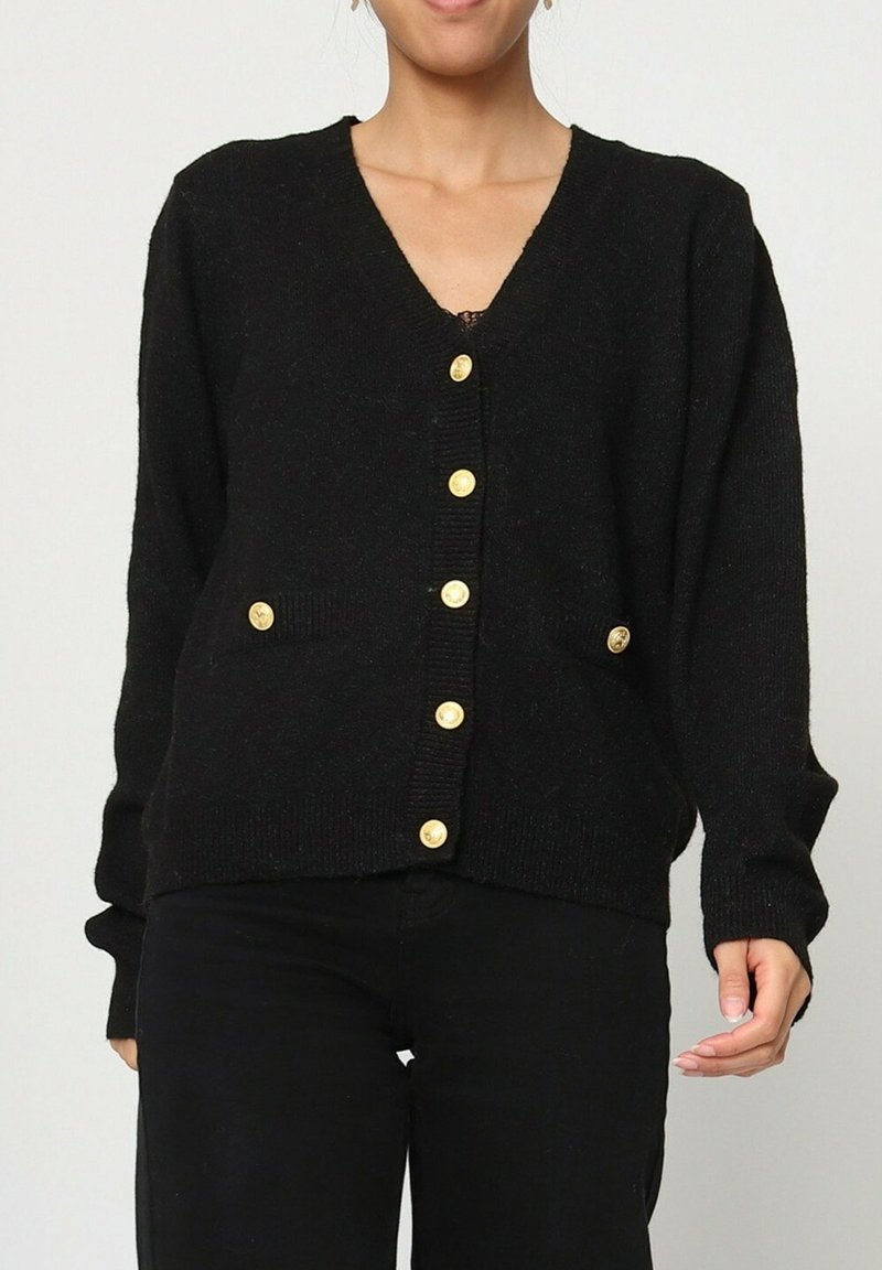 Cardigan noir avec un col en V, des manches longues et une fermeture à boutons. Il présente des boutons dorés et des poches latérales. Texture douce et coupe décontractée.