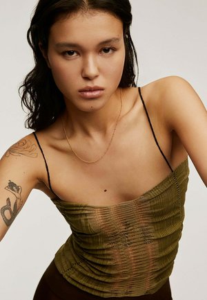 Top de color verde oliva con un diseño texturizado y ajustado, que presenta tirantes delgados negros y un efecto de capas. Un collar dorado añade un detalle.
