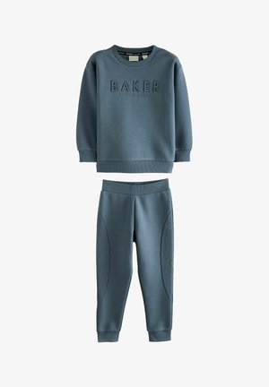 Dvou dílná souprava na jogging v měkké modré tkanině. Mikina má vyvýšený text "BAKER", zatímco kalhoty mají hladké a texturované detaily po stranách.