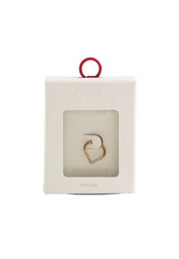 Złota kolczyk w kształcie serca z przezroczystym akcentem z kryształka, prezentowany w białym pudełku z czerwoną rączką. Widoczny stalowy sztyft.