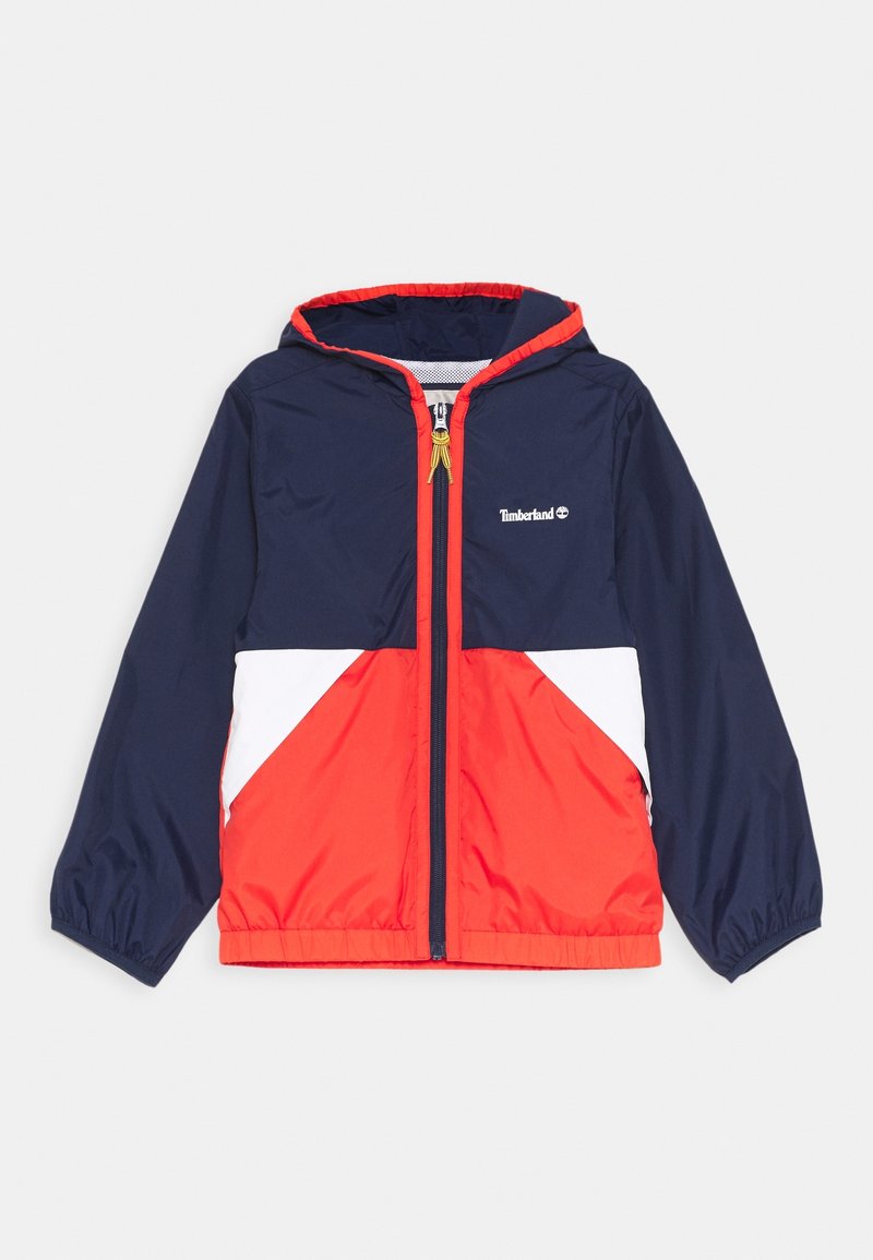 Marineblau und rote Kapuzenjacke mit weißen Akzenten, aus leichtem Material gefertigt. Verfügt über einen Frontreißverschluss und elastische Bündchen. Timberland-Logo auf der Brust.