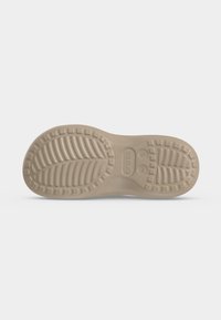 Εξωτερική σόλα μπεζ παπουτσιού Crocs που δείχνει υφή πέλματος και ένδειξη μεγέθους W 5 σε απλό λευκό φόντο.
