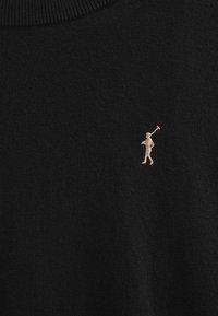 Czarny sweter robiony na drutach z okrągłym dekoltem. Posiada mały beżowy haft przedstawiający postać trzymającą kij po lewej stronie klatki piersiowej.