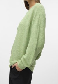 Grüner gestrickter Pullover mit lockerer Passform, langen Ärmeln und ribbeltem Saum. Hergestellt aus einem weichen, strukturierten Stoff.