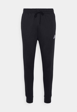 Pantalones de chándal negros con cintura elástica y cordón; cuenta con un pequeño logo blanco de Adidas en la pierna izquierda; diseño de pierna ajustada.