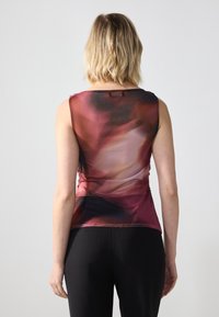 Débardeur sans manches dans un dégradé de tons rouges et violets, fabriqué en tissu léger ; présente un dos en scoop et de subtils plis sur les côtés.