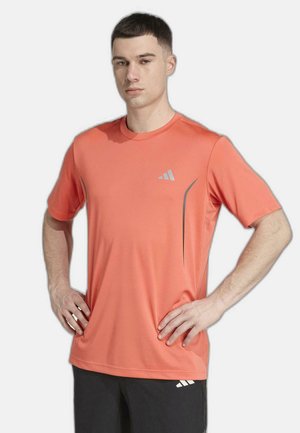 Camiseta deportiva de manga corta en coral brillante, hecha de tela suave y transpirable, con un logotipo reflectante y elegantes detalles de costuras.