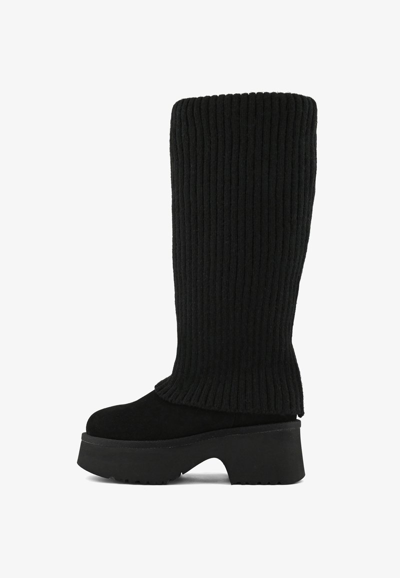 Černá kozačka po lýtko s masivním podpatkem a žebrovaným pleteným vrškem, který sahá od podešve až k vrcholu holeně.