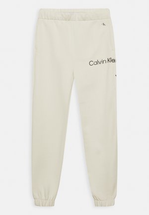 Off-white Calvin Klein joggingbroek met elastische tailleband en boorden, zijzakken en gedeeltelijk zichtbaar zwart merklogo op de rechterdij.
