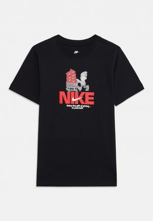 T-shirt noir Nike avec un personnage de dessin animé poussant un chariot rempli de boîtes à chaussures rouges et le texte "Enjoy the gift of giving... to yourself."