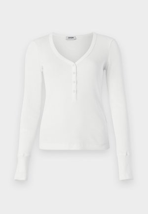 Valge pikakäisiä ribidega henley-tipp, millel on V-kujuline kaelus ja viie nupuga nööri. Omab istepuure ja sujuvat tekstuuri.