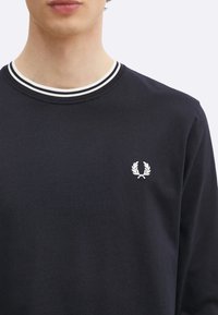 Marineblauwe katoenen sweatshirt met ronde hals, voorzien van een witte gestreepte ribkraag en een klein geborduurd logo op de borst.