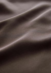 Brązowa tkanina o gładkiej, miękkiej teksturze, z subtelnym drapowaniem i lekko błyszcząca powierzchnią. Skoncentruj się na kolorze i jakości materiału.