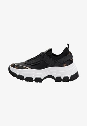 Black sneaker with a chunky white sole, textured materials, elastic laces, and subtle logo details. Features a sleek, modern design.