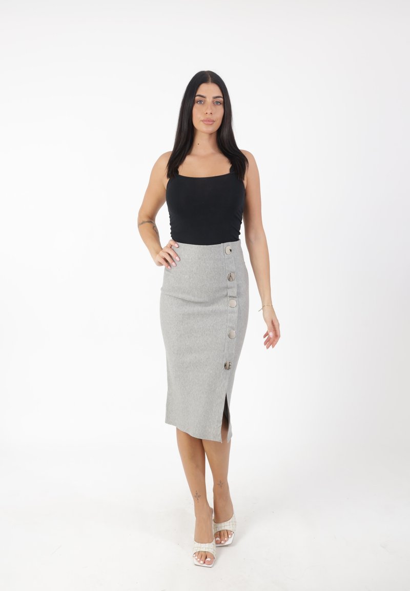 Grijze kokerrok met zijsplit en metalen knoopaccenten, gecombineerd met een zwarte tanktop. Soepele textuur, lengte tot halverwege het onderbeen.