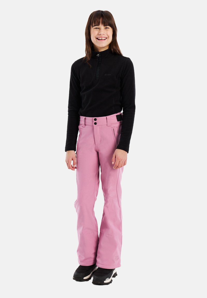 Ružové lyžiarske nohavice majú rovný strih s vysokým pásom a dvoma gombíkmi. V kombinácii s čiernym topom s dlhým rukávom a čiernymi čižmami.