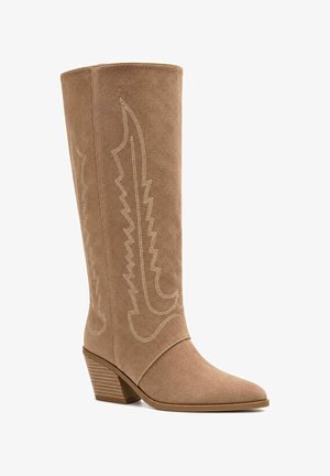 Kniehoher Westernstiefel aus beigem Wildleder mit dekorativer Stickerei, Blockabsatz und spitzer Spitze, auf schlichtem weißen Hintergrund abgebildet.