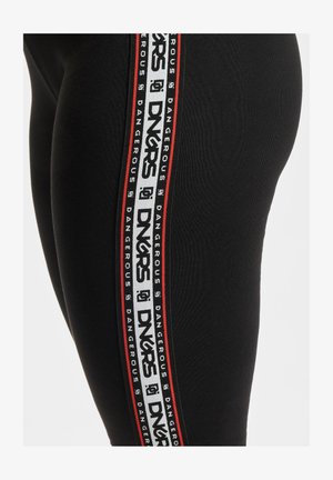 Juodos leggingai su šonine juostele, kurioje kartojasi baltos ir raudonos spalvos "DNGRS" logotipas, pagaminti iš tamprios medžiagos su lygiu paviršiumi.