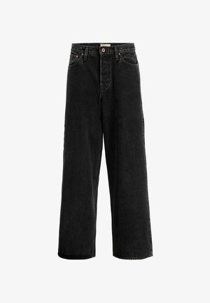 Hvid bomulds t-shirt med kortærmer, parret med løstsiddende sorte denim jeans og beige sneakers med hvide detaljer.