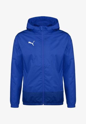 Cazadora cortavientos azul de Puma con capucha, cierre frontal y logo blanco de Puma en el lado izquierdo del pecho, puños elásticos y panel base en azul oscuro.