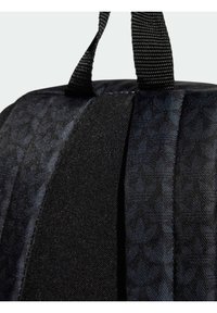 Črn nahrbtnik iz tkanine z teksturiranim dizajnom, ki ima trdne črne ročaje in eleganten, zaobljen obliko.