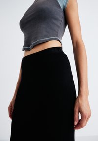 Crop top gris avec un col contrastant bleu clair, associé à une jupe en tricot noire taille haute. Les deux vêtements présentent une coupe près du corps.