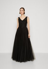 Rochie de seară neagră cu un bust din dantelă ajustat, având broderie complicată. Fustă din tull vaporos, decolteu rotund și bretele ajustabile.