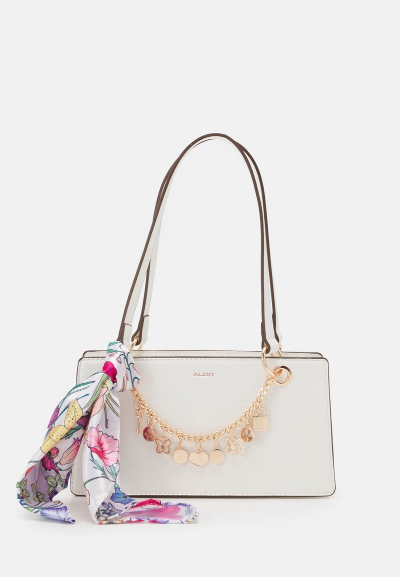 Borsa bianca con dettagli in catena dorata e charm decorativi, dotata di doppi manici marroni. Accompagnata da una sciarpa in seta con motivo floreale.