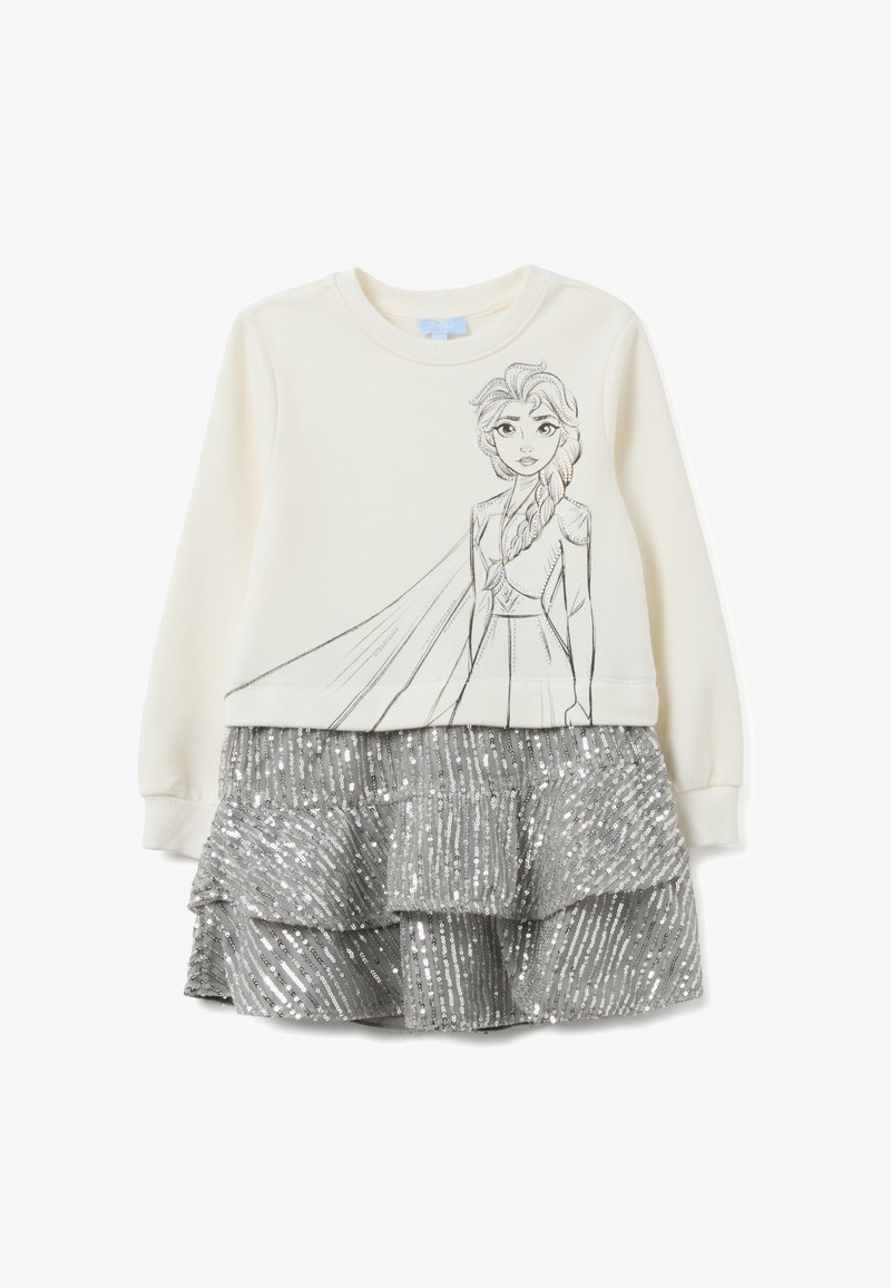 Felpa color crema con il contorno nero di un personaggio sul davanti, abbinata a una gonna a strati con paillettes argento.