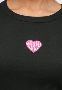 Čierne rebrované tričko s ružovou výšivkou v tvare srdca a textom "SANTA CRUZ" v štýlovom písme uprostred.